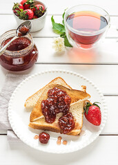 Toasted bread slices with strawberry jam and a jar of jam