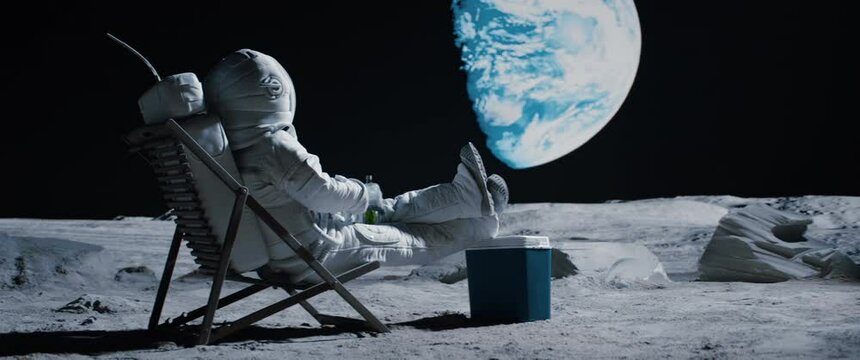Back view of lunar astronaut opens a beer bottle while resting in a beach chair on Moon surface, enjoying view of Earth. Shot with 2x anamorphic lens