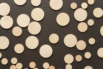 background composed of thin, untreated or natural round wooden shapes - loosely arranged on a dark gray ground - photographed in a top-down style 