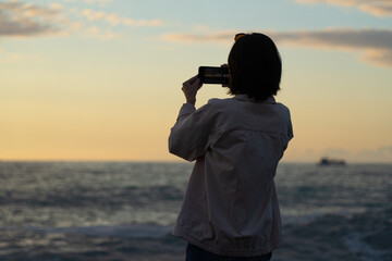 Obraz premium girl photographs the sea sunset