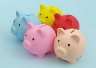 Many colorful piggy banks on blue background. Choose savings fund concept.