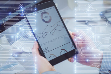 Double exposure of man's hands holding and using a digital device and tech theme hologram drawing. Technology concept.