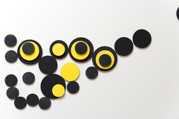 overlapping wooden shapes hand painted in black and yellow - arranged in a loose composition on a light ground - photographed in a top-down orientation