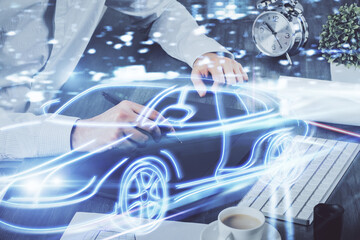 Double exposure of man's hands holding and using a digital device and automobile theme hologram drawing. Technology concept.