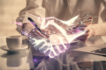 Double exposure of handshake hologram and woman holding and using a mobile device. Partnership concept.