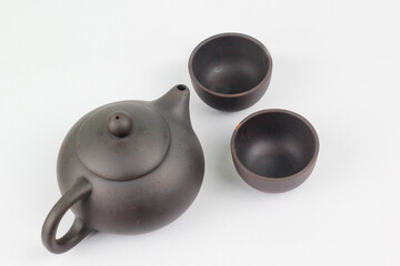 A Chinese black ceramic teapot and teacup isolated on a white background.