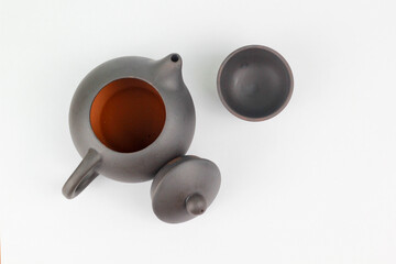 A Chinese black ceramic teapot and teacup isolated on a white background.