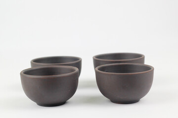 A Chinese black ceramic teapot and teacup isolated on a white background.