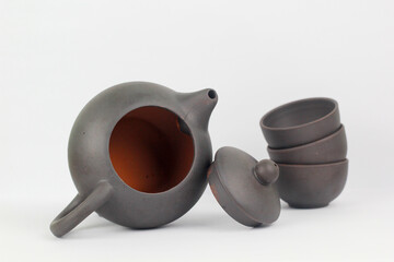 A Chinese black ceramic teapot and teacup isolated on a white background.