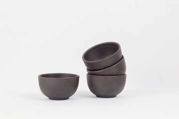 A Chinese black ceramic teapot and teacup isolated on a white background.