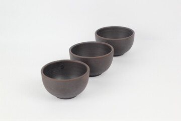 A Chinese black ceramic teapot and teacup isolated on a white background.