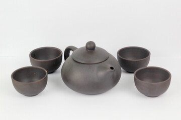 A Chinese black ceramic teapot and teacup isolated on a white background.