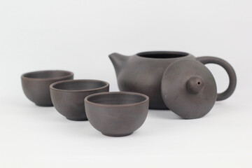 A Chinese black ceramic teapot and teacup isolated on a white background.