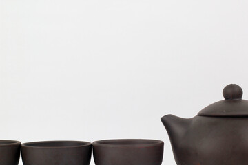 A Chinese black ceramic teapot and teacup isolated on a white background.