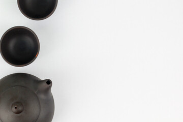 A Chinese black ceramic teapot and teacup isolated on a white background.