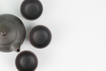 A Chinese black ceramic teapot and teacup isolated on a white background.