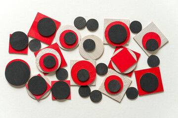 painted black, red and pearl white laser cut wooden plywood shapes, loosely arranged on a light...