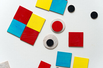 laser-cut plywood shapes hand painted in red, yellow, blue, pearl white, and black loosely arranged...