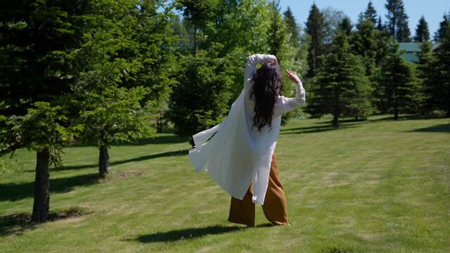 dance improvisation a woman in a white cape dances in a park in a trance state