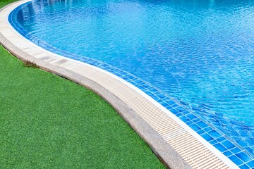 Wide swimming pool and green artificial turf inside the villa