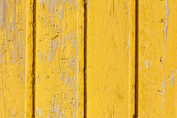 Background of yellow, peeling paint on an old wooden wall