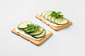 Tasty crackers with cheese and cucumber on grey background