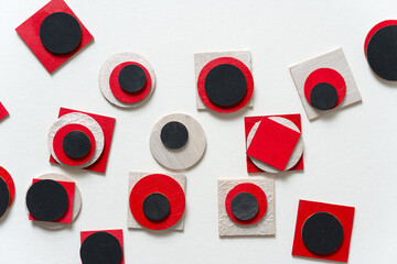 painted red, flat black, and pearl white laser cut wooden plywood shapes, loosely arranged on a...