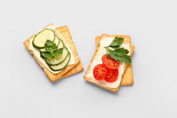 Tasty crackers with cheese, tomatoes and cucumber on grey background