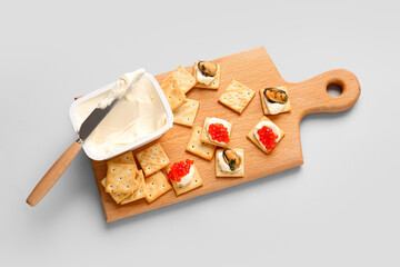 Board with tasty crackers and cheese on grey background