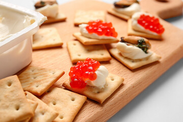 Tasty crackers with cheese, red caviar and mussels on wooden board, closeup