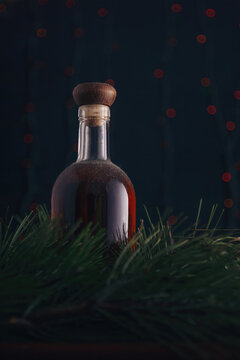 Old Cellar Dusty Bottle Of Brandy, Scotch, Whiskey, Cognac On Blurry Christmas Garland Lights Bokeh Background, Green Pine Branches. Vertical Shot