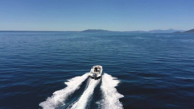 Aerial - Tracking shot of couple enjoying summer speeding on a motorboat