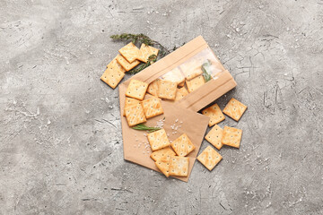 Paper bag with tasty crackers on grunge background