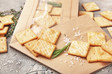 Paper bag with tasty crackers on grunge background, closeup