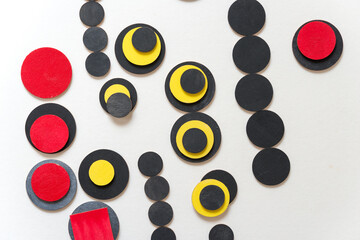 laser-cut plywood shapes hand painted in red, black, and yellow loosely arranged on white - photographed from above in a flat lay style