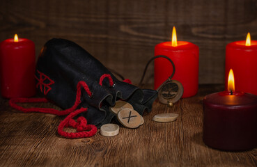 Gebo rune, a bag of runes, and a background of candles with selective focus.The meaning of the rune...