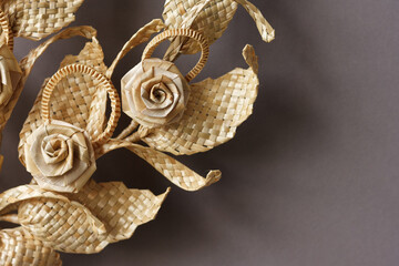 Branch with leaves and flowers is made of straw. Straw wall decoration. The products are made of straw. Decoration of straw on a gray white background