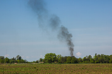 Fototapeta na wymiar Black smoke over the field on a background of the sky. ecology