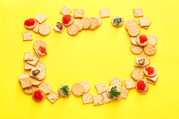 Frame made of tasty crackers on color background