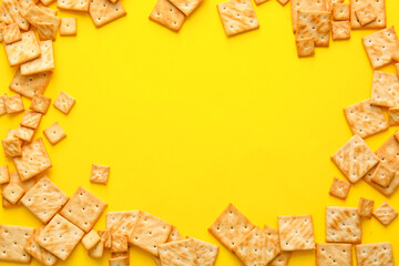 Frame made of tasty crackers on color background