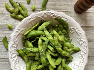 Steamed edamame in a decorative white bowl, top view 