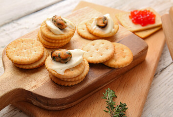Tasty crackers with cheese and mussels on light wooden background, closeup