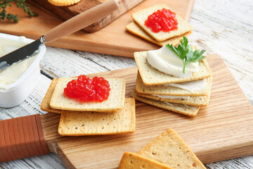Tasty crackers with cheese and red caviar on light wooden background, closeup