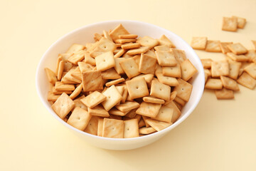 Bowl with tasty crackers on color background