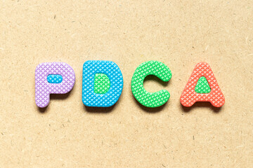 Foam alphabet letter in word PDCA (Abbreviation of plan do check act) on wood background