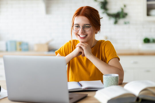 Online learning, portrait of red-haired happy caucasian female freelancer or smiling woman student using a laptop for a video call with a teacher, distance education concept