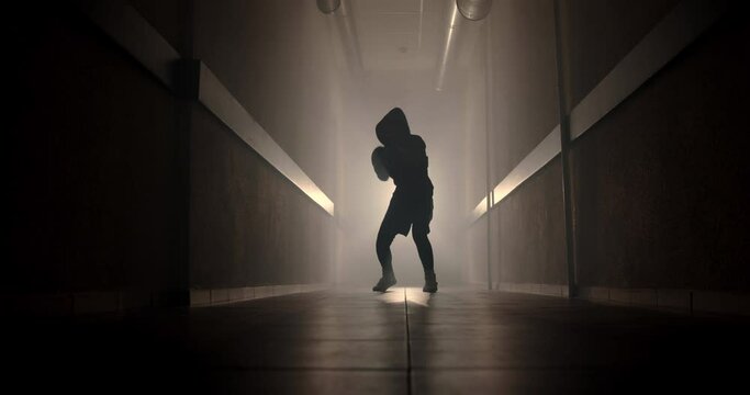 Boxer boxing with a shadow in a semi-dark corridor with a backlight behind his back, slow motion. Videos for motivation, goal achievement, success