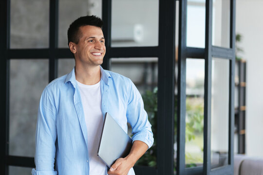 Headshot portrait of  caucasian successful freelancer or student with laptop in casual clothes, stands in office or college, smiling, business concept