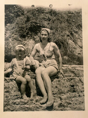 Germany - CIRCA 1930s: Mother and small kid sitting in beach. Vintage archive Art Deco era photography
