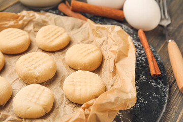 Plate with uncooked cookies on dark wooden background, closeup